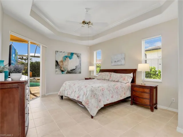 Bedroom with a tray ceiling, access to exterior, ornamental molding, and multiple windows