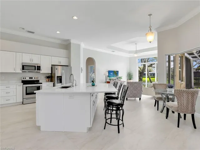 Kitchen featuring appliances with stainless steel finishes, open floor plan, white cabinetry, light countertops, and arched walkways