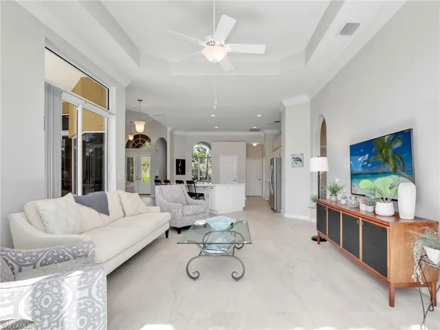 Living area with arched walkways, a tray ceiling, a ceiling fan, and recessed lighting