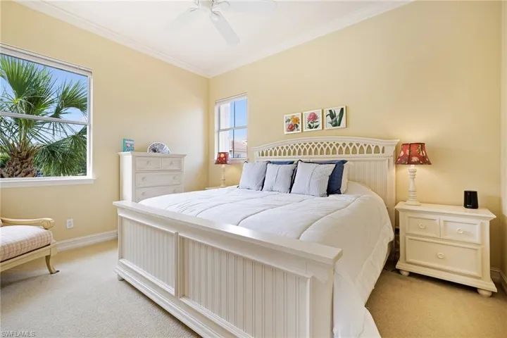 Bedroom with light colored carpet, crown molding, baseboards, and ceiling fan