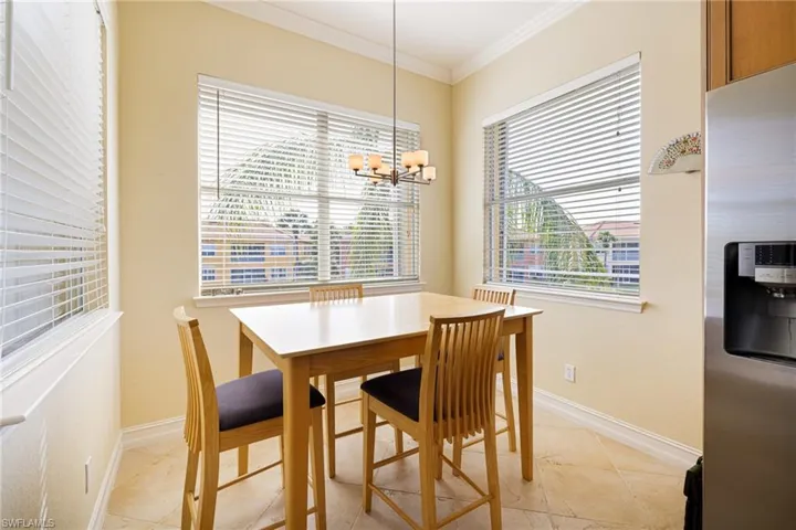 Dining area featuring crown molding, a chandelier, baseboards, and light tile patterned flooring