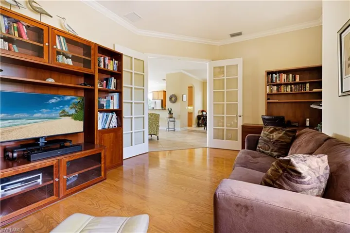 Living room featuring french doors, ornamental molding, light wood finished floors, and baseboards