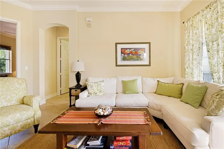 Living room with ornamental molding, arched walkways, and baseboards
