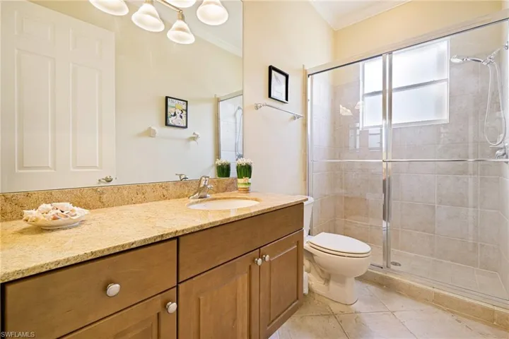 Full bath with ornamental molding, toilet, a stall shower, vanity, and tile patterned floors