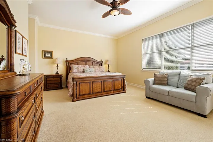 Bedroom featuring ornamental molding, light carpet, baseboards, and a ceiling fan