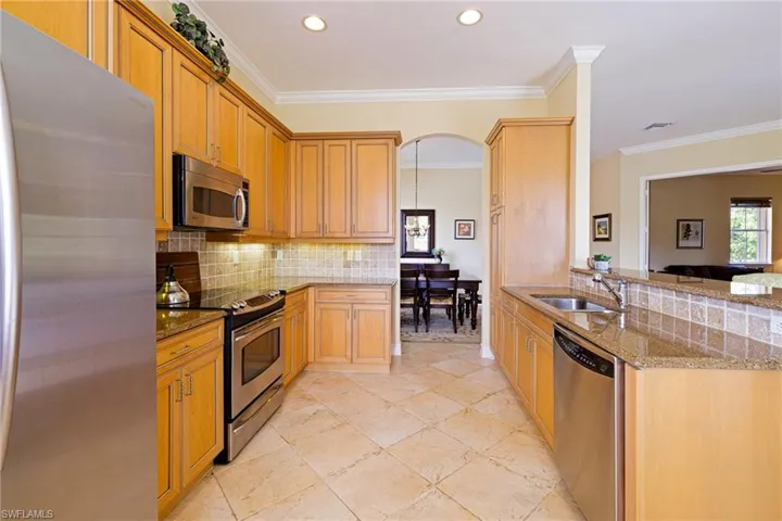 Kitchen featuring appliances with stainless steel finishes, a sink, light stone counters, tasteful backsplash, and a peninsula