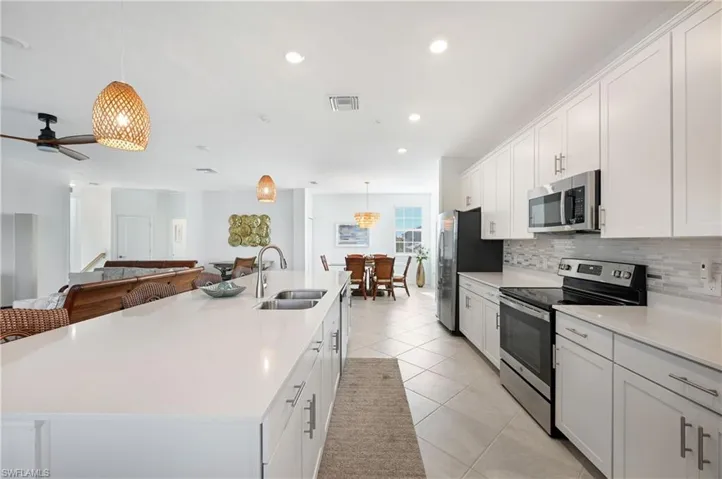 Kitchen with stainless steel appliances, hanging light fixtures, white cabinetry, a large island, and recessed lighting