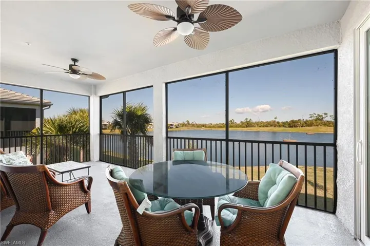 Sunroom / solarium featuring a ceiling fan, a water view, outdoor dining space, and a textured wall