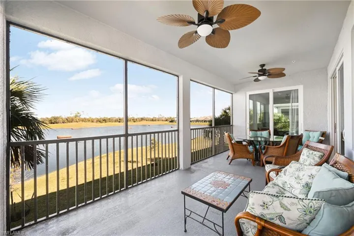 Sunroom featuring outdoor dining area, ceiling fan, and a water view