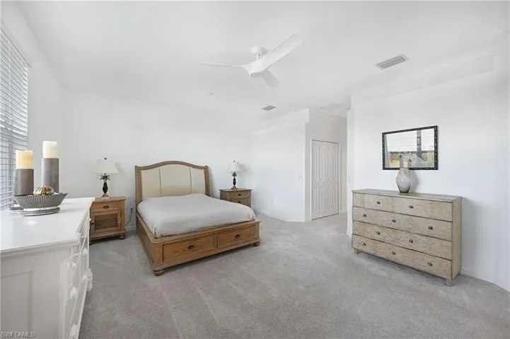 Bedroom featuring light carpet, ceiling fan, and a closet