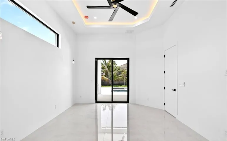 This bright room features a black ceiling fan, recessed lighting, and a tray ceiling