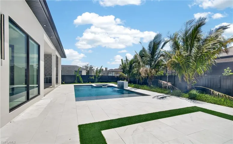 The property features an outdoor patio with light-colored tile flooring, a swimming pool, and an artificial turf area