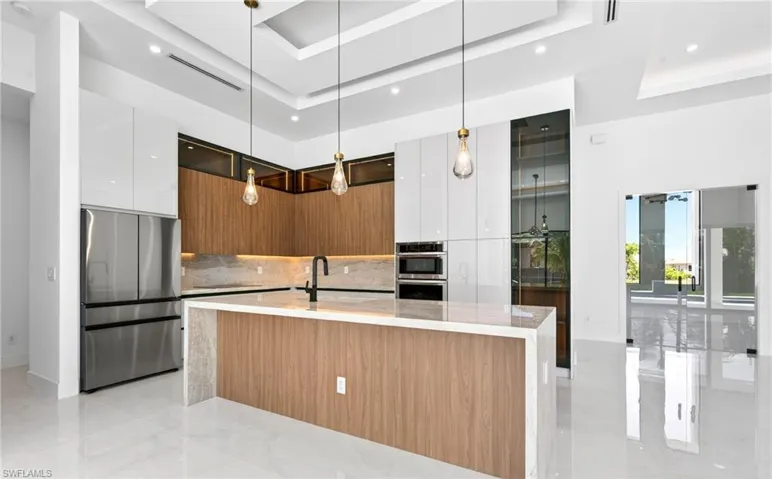 The kitchen features a large island with a light-colored countertop, modern appliances, and sleek cabinetry