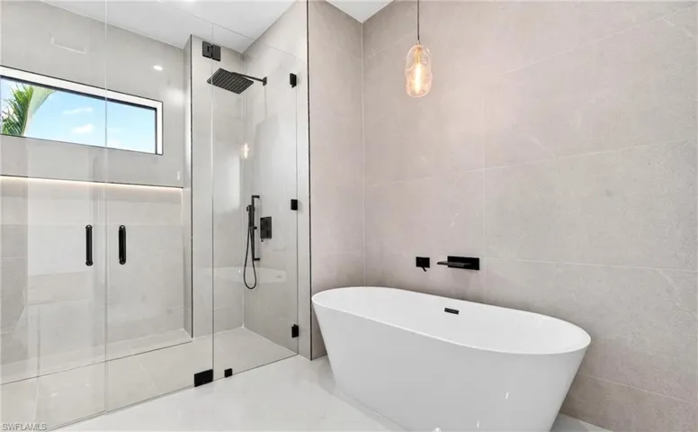 The bathroom features a spacious glass-enclosed shower with matte black fixtures and an overhead window