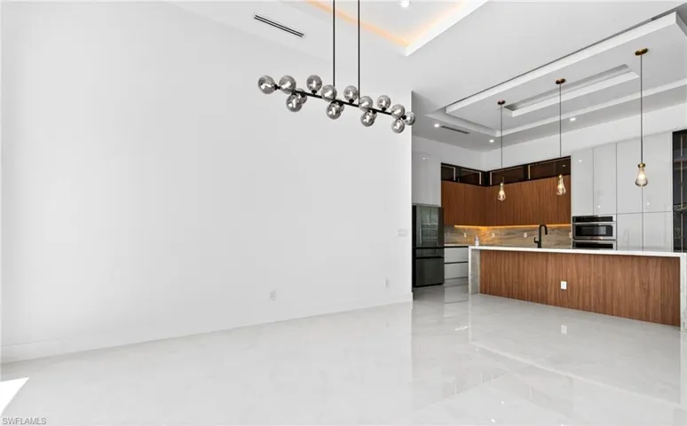 This expansive open-concept room features pristine white tile flooring and high ceilings with recessed lighting