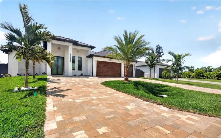 The property features a white exterior with a dark roof and a paved driveway