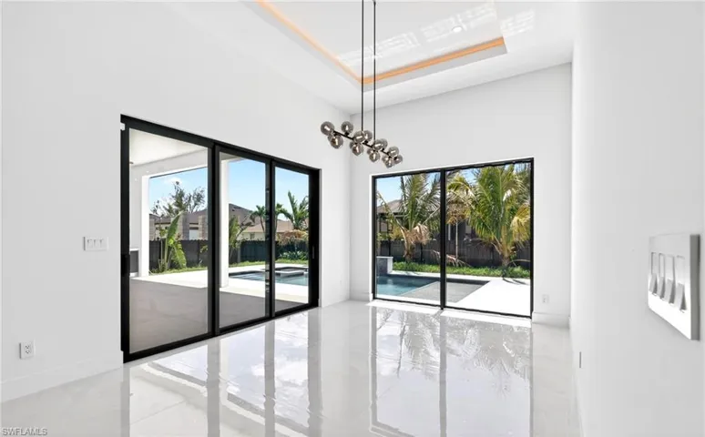 This bright interior space features high ceilings, a contemporary light fixture, and reflective flooring