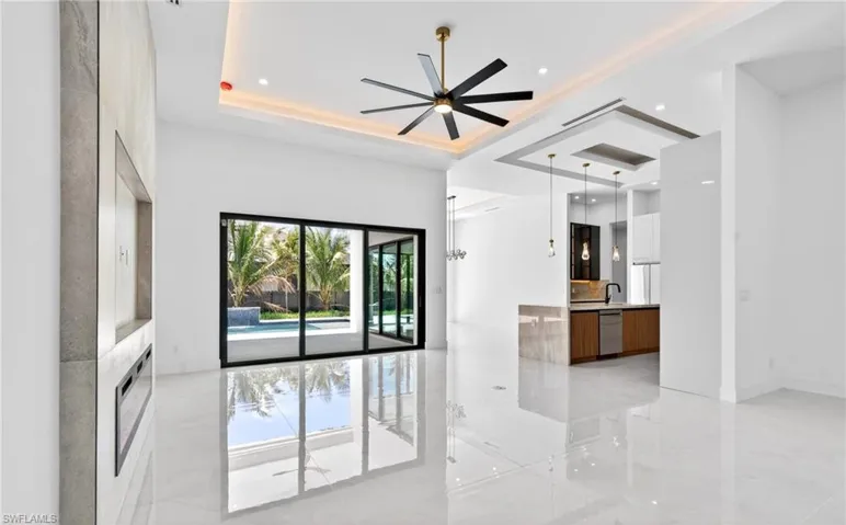 Spacious main living area featuring glossy tiled floors, a modern ceiling fan, and large sliding glass doors leading to the exterior pool area