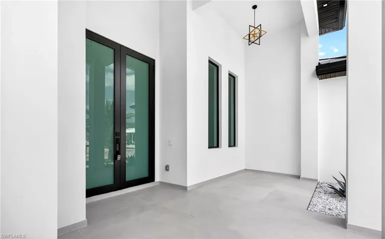 The property features a grand entrance with double glass doors, a geometric style light fixture, and vertical windows providing natural light