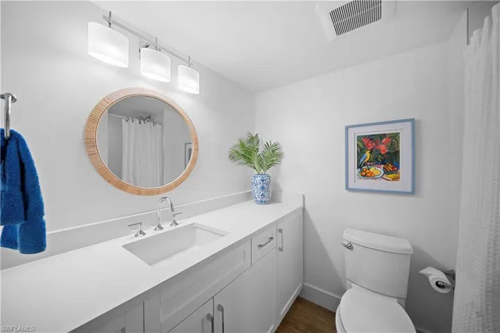 Full bath with vanity, a shower with shower curtain, and dark wood-style flooring