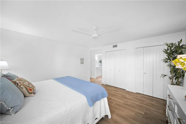 Bedroom featuring two closets, wood finish floors, and a ceiling fan