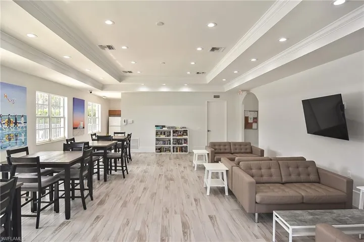 Living room with ornamental molding, a tray ceiling, and light hardwood / wood-style flooring
