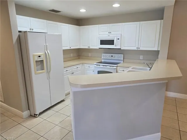Kitchen featuring white cabinets, kitchen peninsula, sink, and white appliances