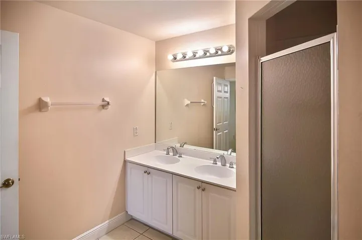 Bathroom featuring tile patterned flooring, vanity, and an enclosed shower