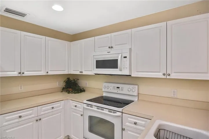 Kitchen featuring white cabinets and white appliances
