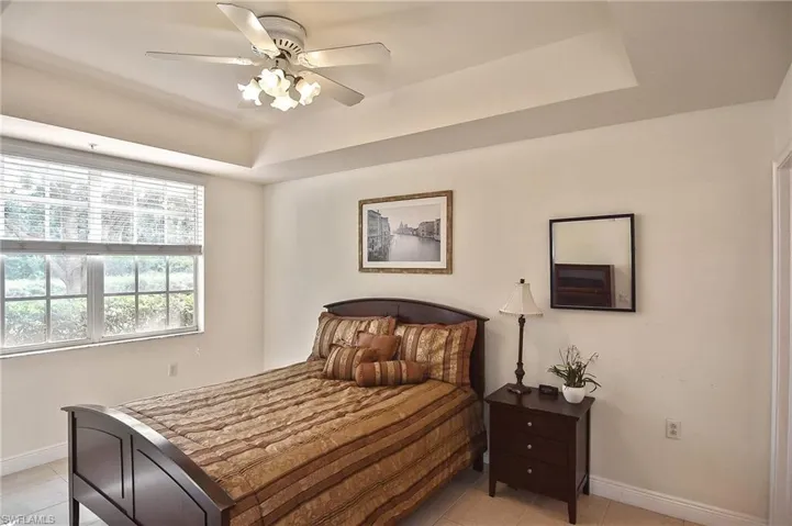 Bedroom featuring a tray ceiling, ceiling fan, and light tile patterned flooring