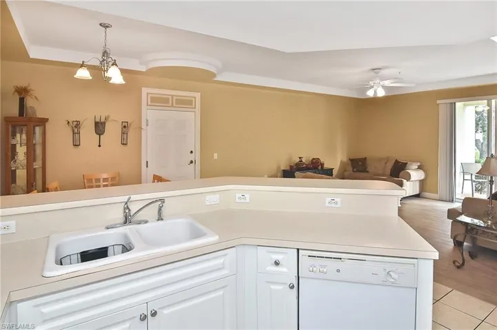 Kitchen featuring light wood-type flooring, ceiling fan with notable chandelier, sink, dishwasher, and white cabinetry