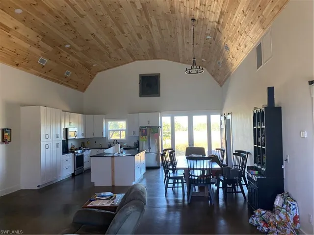 Dining room with high vaulted ceiling, finished concrete floors, and wooden ceiling