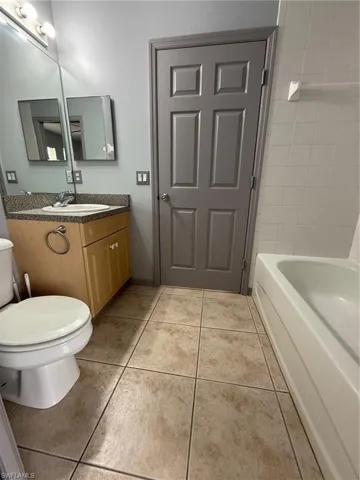 Bathroom featuring a light wood-finish vanity with a stone-look countertop, a built-in sink with chrome faucet, and a large wall-mounted mirror