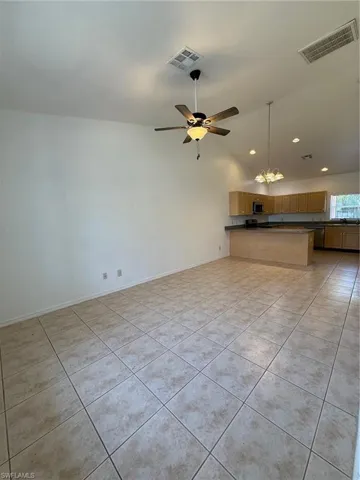 Spacious room featuring vaulted ceilings, a ceiling fan with integrated lighting, and light-toned tile flooring