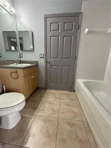 Bathroom featuring a light wood-finish vanity with a built-in sink, speckled countertop, and chrome faucet