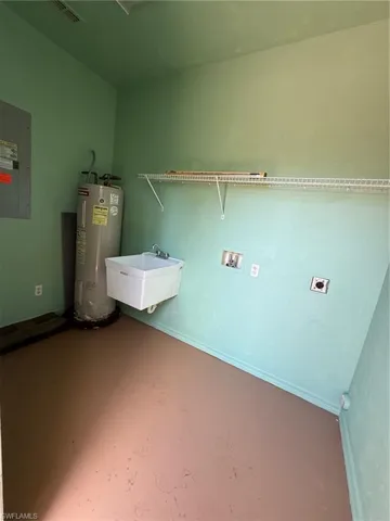 Laundry area featuring a utility sink, water heater, and a wall-mounted wire shelf
