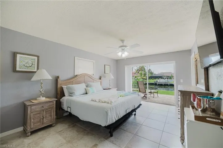 Primary Bedroom with King size bed, view of canal & pool with patio slider.