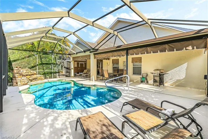 View of swimming pool featuring area for grilling, glass enclosure, and a patio