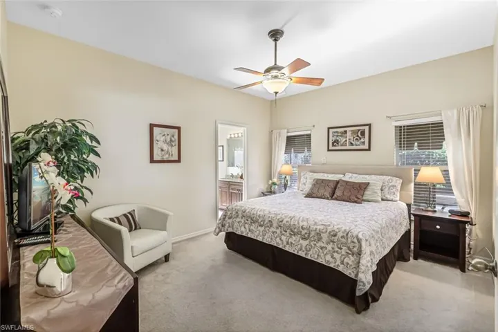 Carpeted bedroom with connected bathroom and ceiling fan