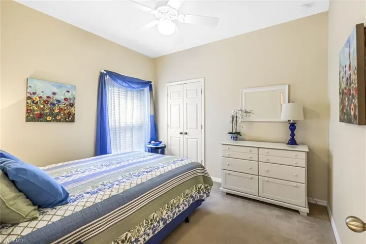 Carpeted bedroom with ceiling fan and a closet