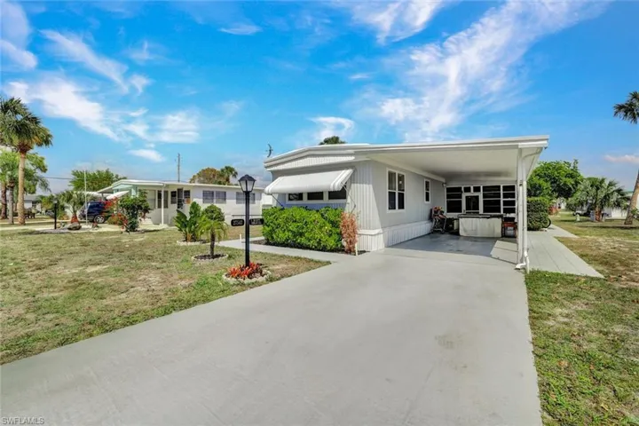 Manufactured / mobile home with a front yard, an attached carport, and driveway