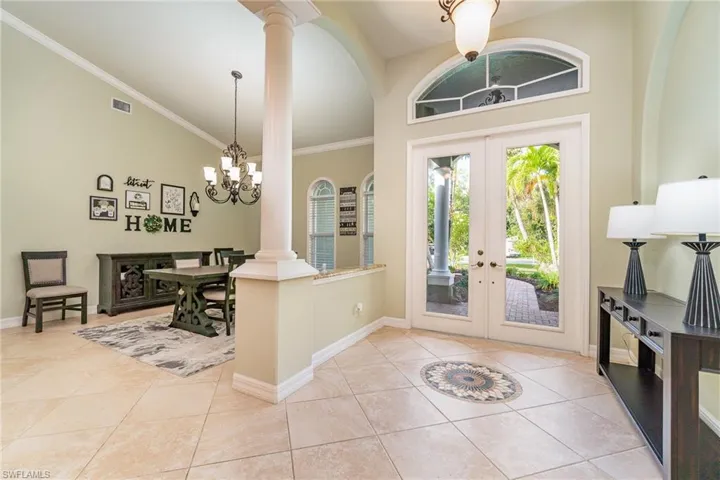 Foyer with  light tile patterned floors, ornamental molding, and french doors