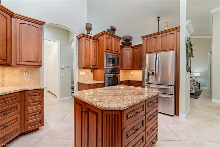 Kitchen featuring backsplash, a kitchen island, light tile patterned floors, and appliances with stainless steel finishes