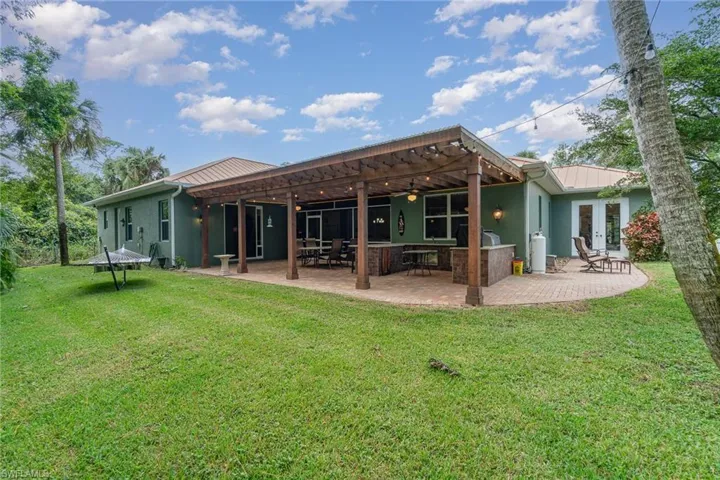 Back of house with a lawn, a patio area, and a pergola