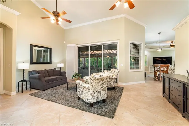 Tiled sitting  room with high vaulted ceiling, ceiling fan, and crown molding