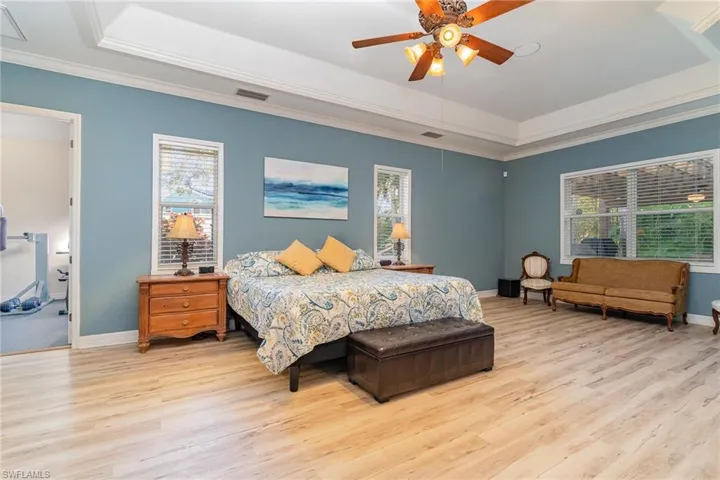 Bedroom with vinyl wood-style floors, ceiling fan, and crown molding