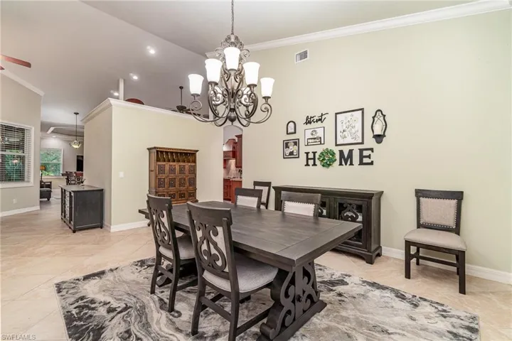 Dining room with light tile floors, volume ceiling, and crown  molding