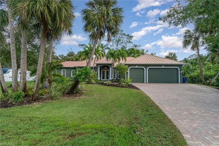 View of front of home with palm trees, Metal roof  fenced side  yard