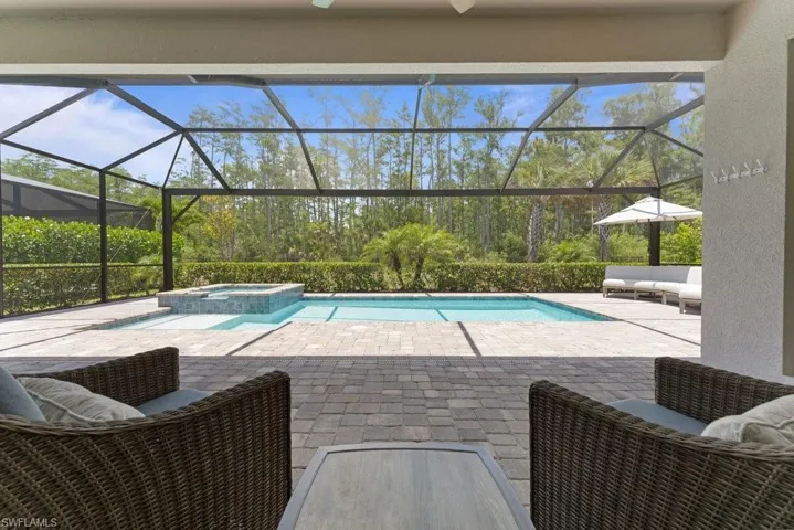 View of pool with a patio, a pool with connected hot tub, glass enclosure, and outdoor lounge area