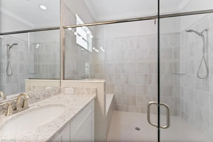 Full bath with ornamental molding, vanity, a shower stall, and tile walls